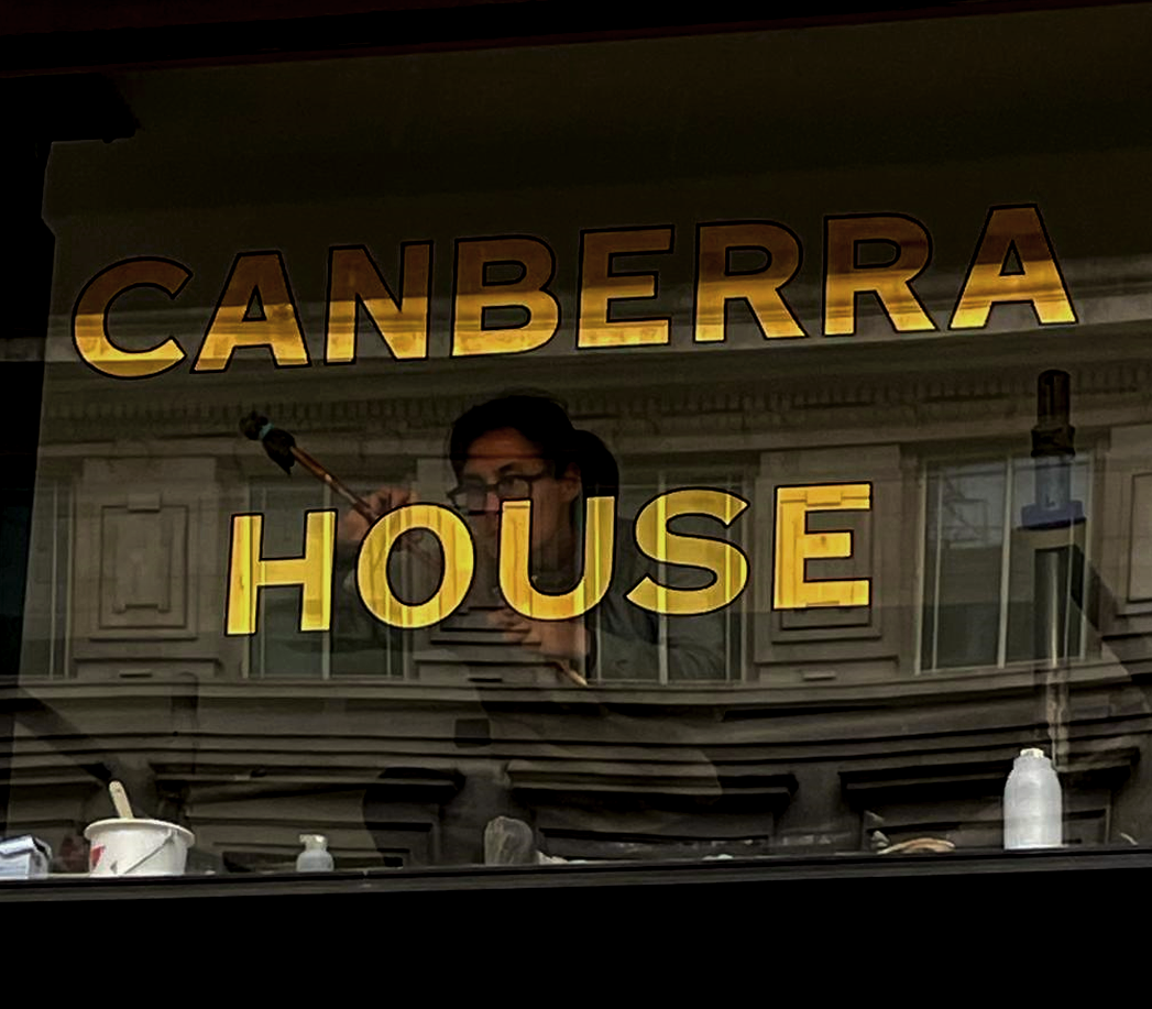 Seraina Gilding lettering on glass at Canberra House Central London sign gilder. Gold leaf lettering. Soho Bold for Canberra house LDN