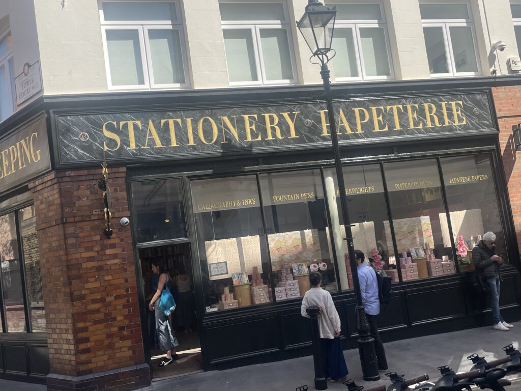 Storefront of a stationery shop with a large black marble sign in gold lettering reading 'STATIONERY HAPETERIE'.